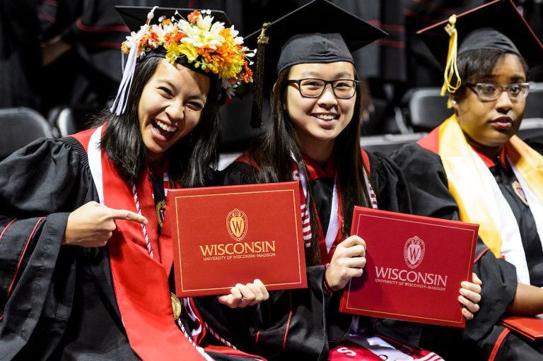 New graduates in academic attire show off their diploma covers.