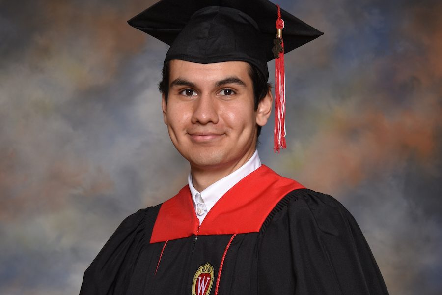 Portrait of UW graduate in academic attire holding diploma cover.