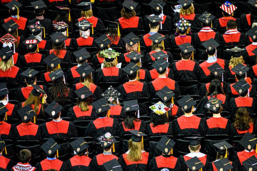 View from above of showing group of graduates seated wearing red and black academic attire.