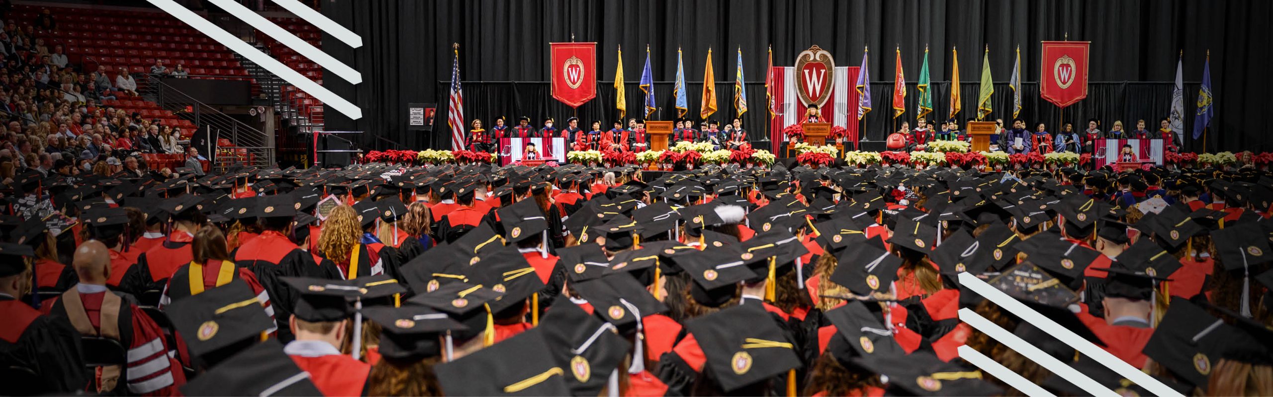 UW–Madison Chancellor, Jennifer Mnookin, on stage addressing graduates wearing mortarboards and gowns.