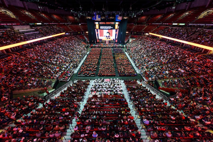 Aerial view within arena filled with graduates and their guests.