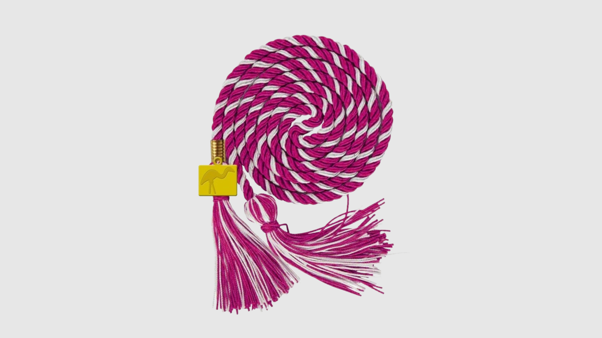 A pink and white striped graduation cord with a gold charm that has a flamingo etched on it. 