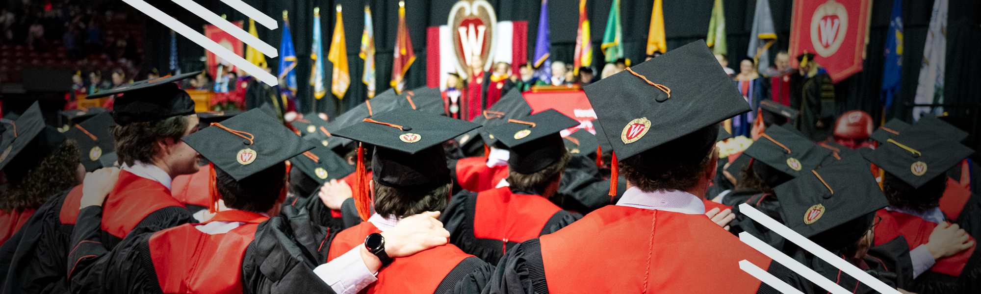 Graduates in red and black regalia sing Varsity, UW–Madison's alma mater, at the close of the Winter 2025 Commencement ceremony at the Kohl Center.